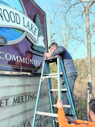 Don Smith helps touch up the sign.