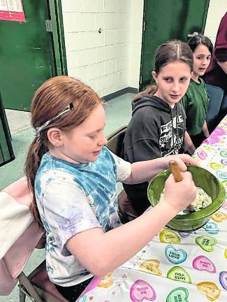 Brooke Prospero mixes ingredients while Sara Szarek and Aria Bundy look on.