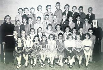 <b> St. Joseph Parochial School students (pictured) in the 1960s could ride to school on public school bus established routes. Special bus routes directly to Our Lady Queen of Peace and St. Joseph Parochial Schools were denied because of possible violation of the law separating church and state. Father Cornelius Kelly is pictured with students. Photo courtesy Irene Bishop Zak</b>