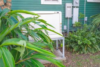 An example of a home standby generator on the side of a house with some natural screening.