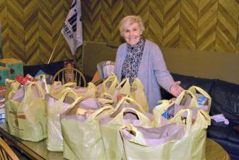 Elks member Barbara Doster stands in front of a table filled with bags of food for the club's annual holiday food drive at the lodge on saturday.