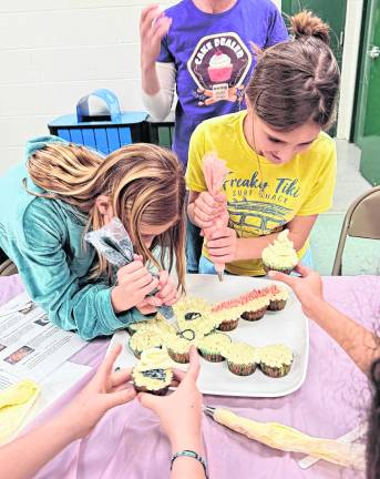 Ella Weidmuller, 9, and Abby Scully, 10, frost cupcakes.