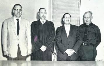 Between 1934 and 1942 when Jack Ryan was appointed to the West Milford Police Force, Police Chief Moeller was the lone lawman for the entire eighty-plus square mile Township of West Milford. Later Louis Hall, James Kemble and James Semento were appointed individually, creating a five-man force until 1959 when five additional patrolmen were appointed. The force grew rapidly after that. Pictured from left that year are Court Clerk George Eckhardt, Judge T. Harry Cahill, Prosecutor Marcus Mandelbaum and Police Chief John H. Moeller. (Photo Ann Genader)