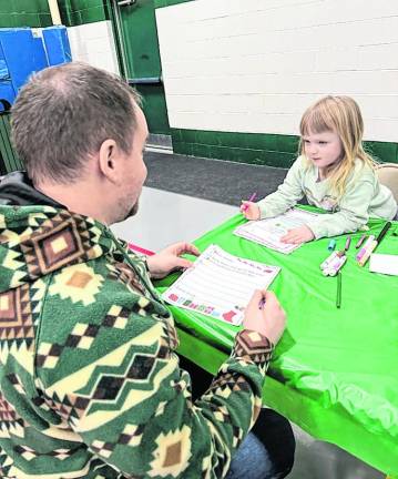 Juniper Savage Foley, 4, of West Milford writes her letter to Santa as her father, Jim Foley, looks on.