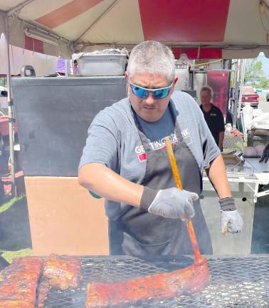 Pitmaster Adolfo Luviano of Joe Smoke Bar-B-Que puts the finishing touches on their award-winning ribs at the 12th annual Rock, Ribs &amp; Ridges festival in Augusta.