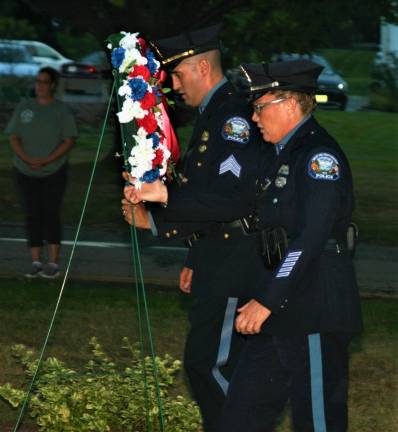 [Police officers lay a wreath at the 9/11 memorial in front of Town Hall Wednesday night. Charles Kim photo]