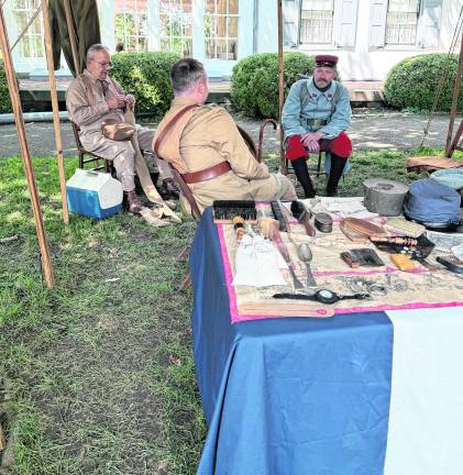 Reenactors sit under a canopy.