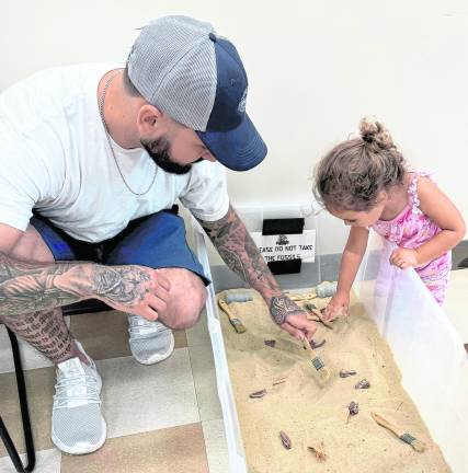 Stevie Donofrio, 3, of West Milford digs for bones as her father, Michael, watches.