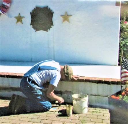 A member of the West Milford Veterans of Foreign Wars Post 7198 repairs cracks in the memorial structure at Veterans Park.