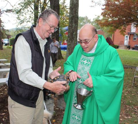 Dave Roche brought Woody, a one-hundred year old Red Legged African tortise for a blessing. Photo by Ginny Raue