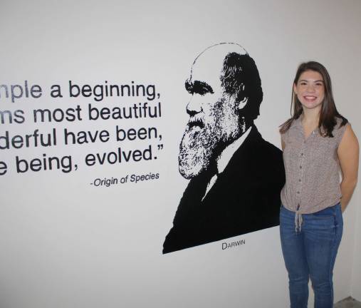 Photo provided Kelly DeNaples of Newfoundland stands by the first of her works of art, this one depicting Charles Darwin, at the Gittleson Hall at Hofstra University.