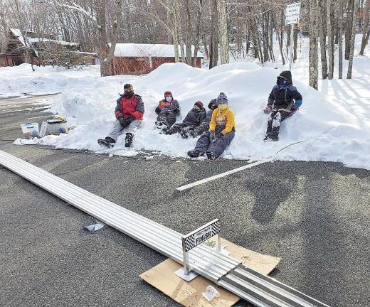 Awaiting the finish: Pack 159’s Arrow of Light den sits in a pile of snow to take in their final pinewood derby race as cub scouts.
