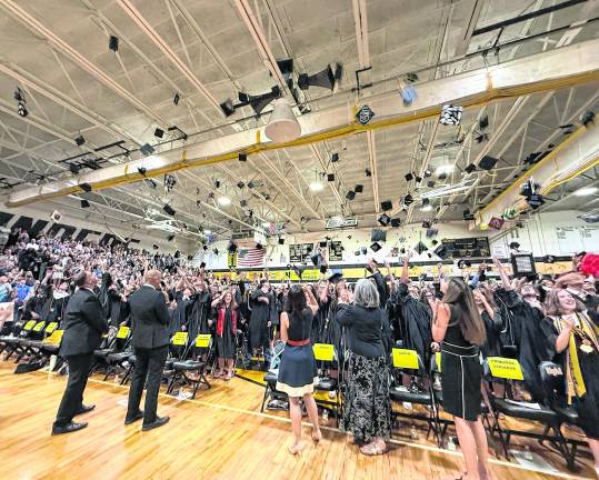 West Milford graduates throw their caps in the air in celebration.
