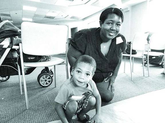 Tonya Ball of West Milford helps her 2-year-old son Jacob Zaro draw on a large roll of paper laid out on the floor for children to express themselves through artwork.
