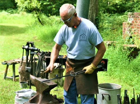 [Wyckoff Blacksmith Gaspar Lesznik conducts a field demonstration of 19th century metal work at the Long Pond Ironworks State Park in Hewitt on Saturday. Charles Kim photo]