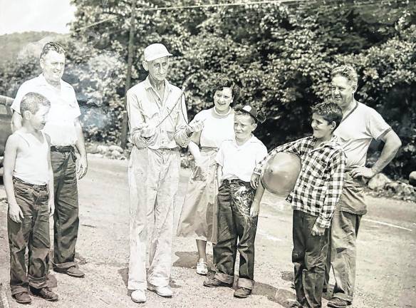 Water dowser “Charlie” Decker demonstrates how he finds a place where a well water supply could be abundant. Seen in a 1950s photo from left are: Peter Gillen Jr., Peter Gillen Sr., Charles Decker, Anna Romlein Struble, Parrick Gillen, Corky Struble, Floyd Struble Sr.