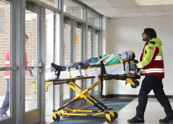 A casualty from the mock incident is taken from the high school on a stretcher to medical personnel waiting outside.