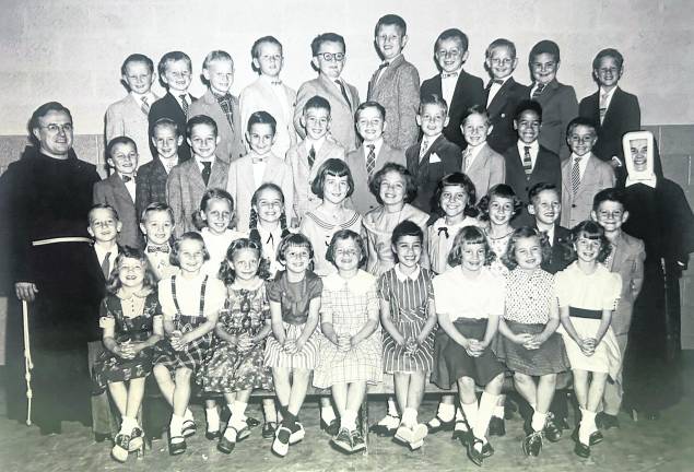 <b> St. Joseph Parochial School students (pictured) in the 1960s could ride to school on public school bus established routes. Special bus routes directly to Our Lady Queen of Peace and St. Joseph Parochial Schools were denied because of possible violation of the law separating church and state. Father Cornelius Kelly is pictured with students. Photo courtesy Irene Bishop Zak</b>
