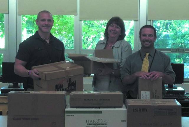 Macopin School Principal Mary Reinhold, Assistant Principal Marc Citro and Richard Dygos hold and stand next to care packages and items being sent to U.S. soldiers in Afghanistan through Operation Thank You.