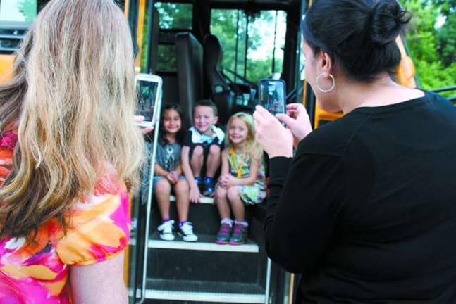 Theresa Cantora, left, and Laura Bonsignore take a photo on the steps of the school bus of their kindergartners, seated from left, Gia Bonsignore, Reilly and Amber Cantora.