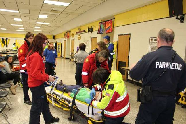 Local EMTs secure one of the actors to a gurney during the drill. These types of drills are important, according to training Lieutenant Dolores Serpe of the West Milford First Aid Squad, because this isn't the typical scene local first responders are used to.