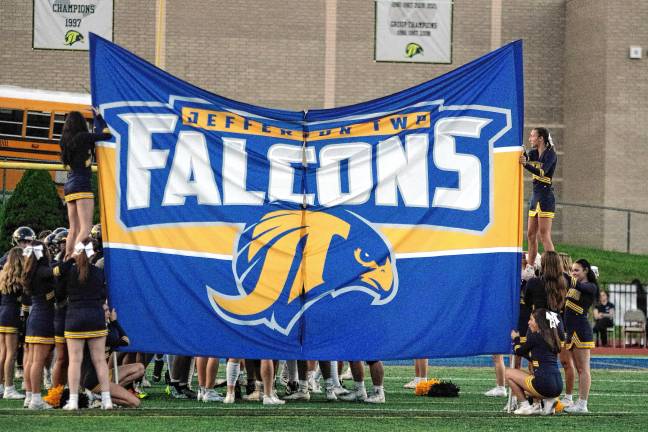 The Jefferson Township High School cheerleaders hold a breakaway banner before the football team makes its entrance.