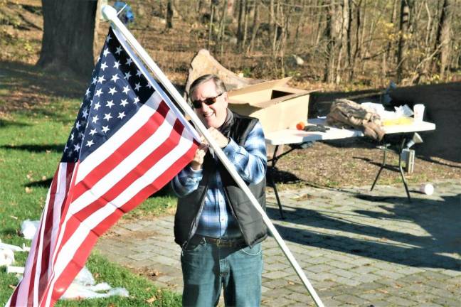 A member of the Rotary prepares a flag for the Heroes display at Bubbling Springs Park.
