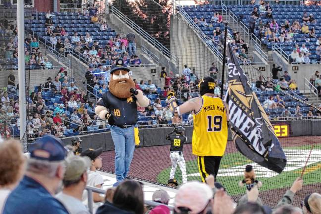 <b>Herbie the Miner and Miner Man perform in front of baseball fans.</b>