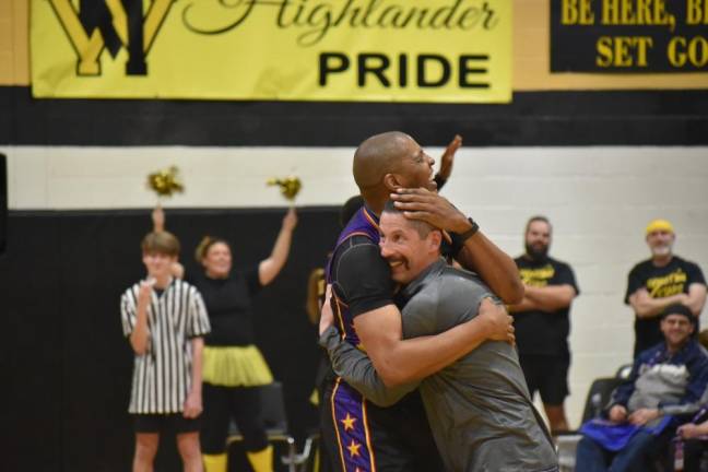 A Harlem Wizards team member hugs Michael Lizza during a break in the game.
