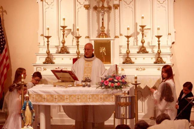 Photos by Ginny Raue First Communicants gathered around the altar before receiving the Eucharist for the first time.