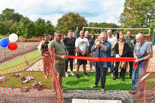 Mayor Michele Dale cuts a ribbon to officially open the new volleyball court at Bubbling Springs Park. With her are township officials and West Milford High School volleyball players and coaches. (Photos by Rich Adamonis)