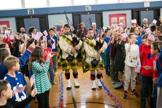 Bagpipers lead veterans into the hall at Paradise Knoll School as children and staff wave flags and applaud. photos by stephen miller