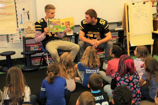 Highlanders football players Andrew Finke (12), left, and Anthony Derin (53), read to second-graders in Mrs. Turner's class at the Upper Greenwood Lake Elementary School as part of the Punt, Pass &amp; Read program. photo by don webb