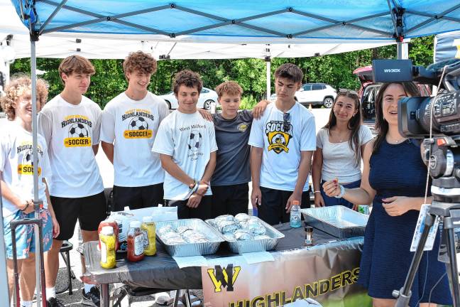 CBS New York correspondent Kristie Keleshian, right, reports from the tailgate and watch party Sunday with members of the high school soccer team behind her.