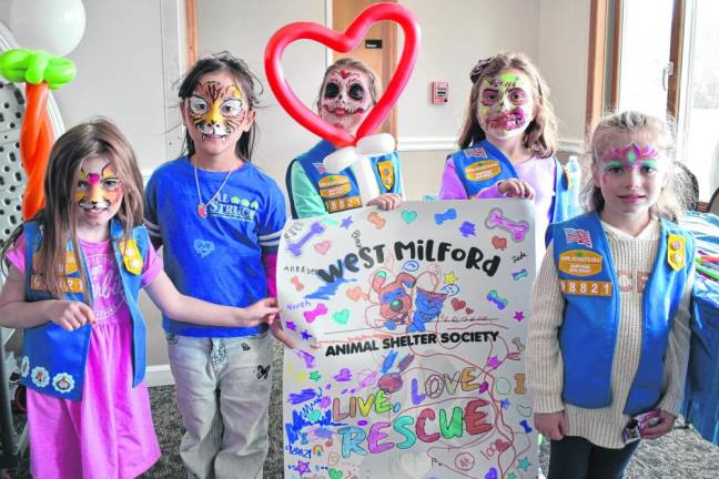 Members of Girl Scouts Troop 98821 hold a poster with caring messages that they made for the West Milford Animal Shelter.