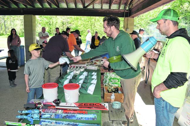 A youngster wins a West Milford Fishing Derby hat presented by Recreation Department Assistant George Christman, center, and Director Dan Kochakji.