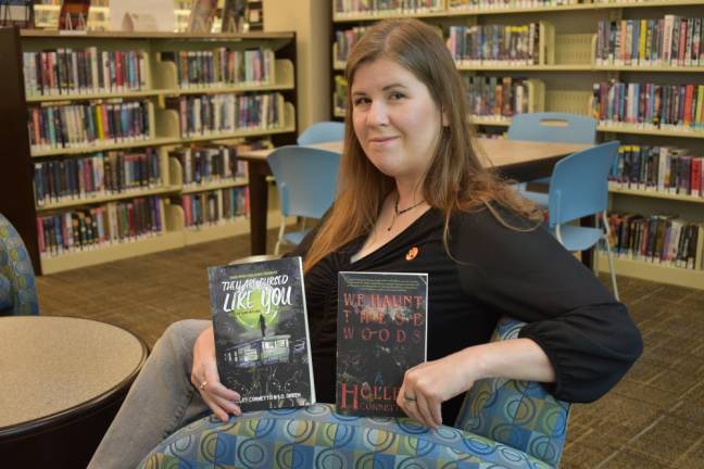 Holley Cornetto holds her horror books, ‘They Are Cursed Like You’ and ‘We Haunt These Woods.’