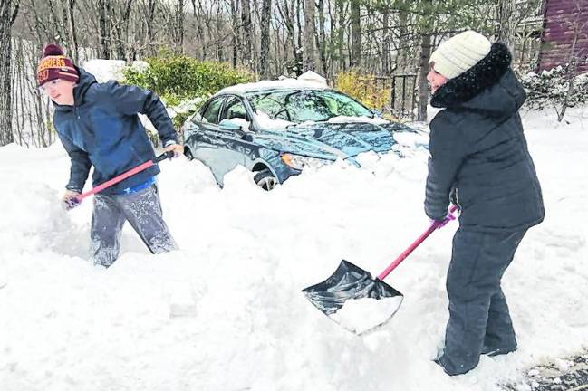 Youngsters Victor, 14, and Olivia, 10, Padilla shovel out a neighbor's car and driveway after the snowfall.