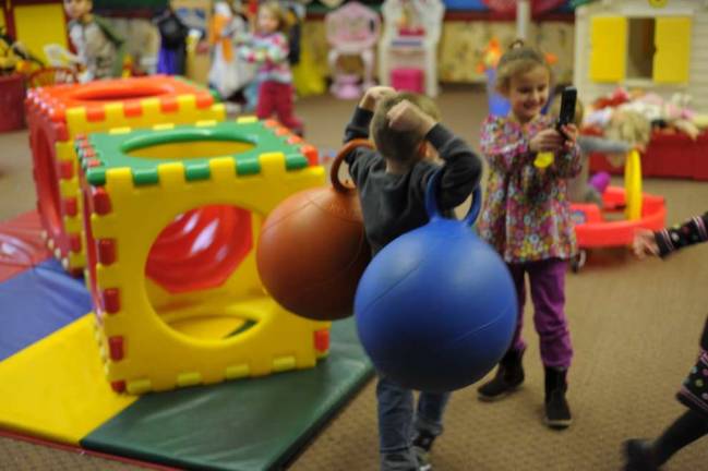 A student from the preschool run by the West Milford Department of Recreation triumphantly cleans up toys in the school's kindergym. (Photo by Joshua Rosenau)