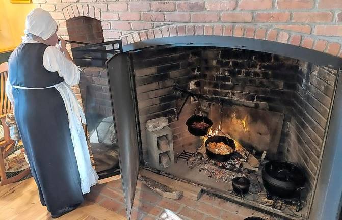 Una Lee uses a blow pipe to stoke the beehive oven fire.