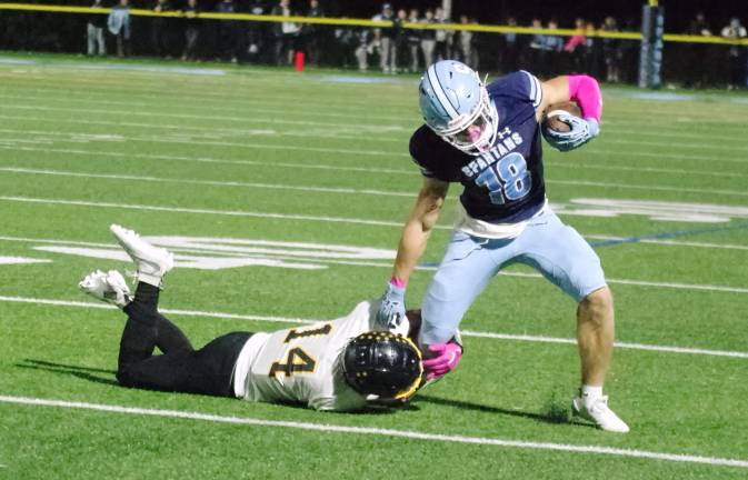 Sparta wideout Christian Brevig tries to break free from the grasp of West Milford defensive back Patrick Foley (14).