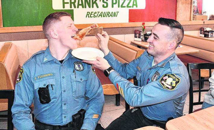 Officer Nolan Ryan feeds a slice of pizza to Officer Jason Fuehring.
