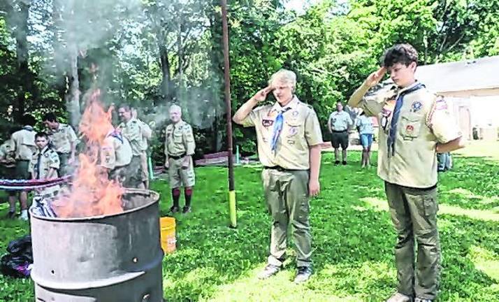 Boy Scouts salute a retired American flag.