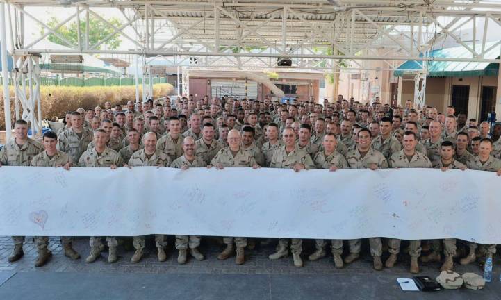 Coast Guard troops hold up the National Christmas Card they received. At center, front is Admiral R.J. Papp, Jr., Commandant, U.S. Coast Guard