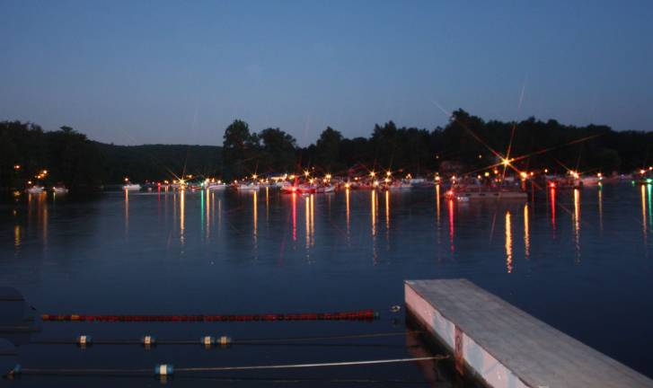 As night falls over Upper Greenwood Lake, the resident's boats are lined up and ready to enjoy the annaul Fourth of July fireworks display. All the boats are kept at a safe distance, away from the damn where the fireworks originate. Before the sky lit up with pyrotechnics the boats on the lake were a show in themselves, their running lights shining on the water, a deep blue sky overhead and almost-full moon adding to the scene. Photo by Ginny Raue