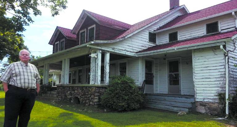 Photo by Dan Durfos/Courtesy of Kerry O'Brien Member of the Friends of the Wallisch Farmstead group, Kerry O'Brien, stands in front of the historic Wallisch home, built in part before 1820. The farmstead, located on Lincoln Avenue in West Milford, is in serious disrepair and the Friends hope to raise funds to stablize the property and awareness of the possibility of losing another piece of West Mlford history.