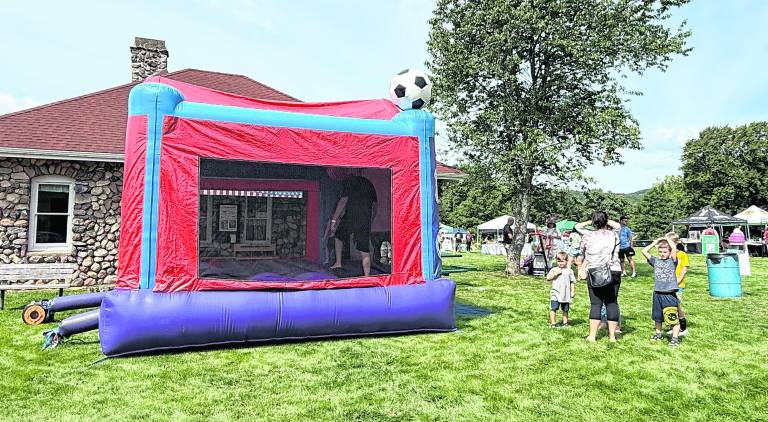 Children and some adults joyfully bounce in the bounce house.