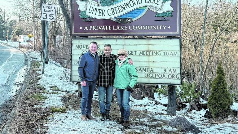 Don Smith, Dennis Decina and Susan Bemel stand in front of the sign.